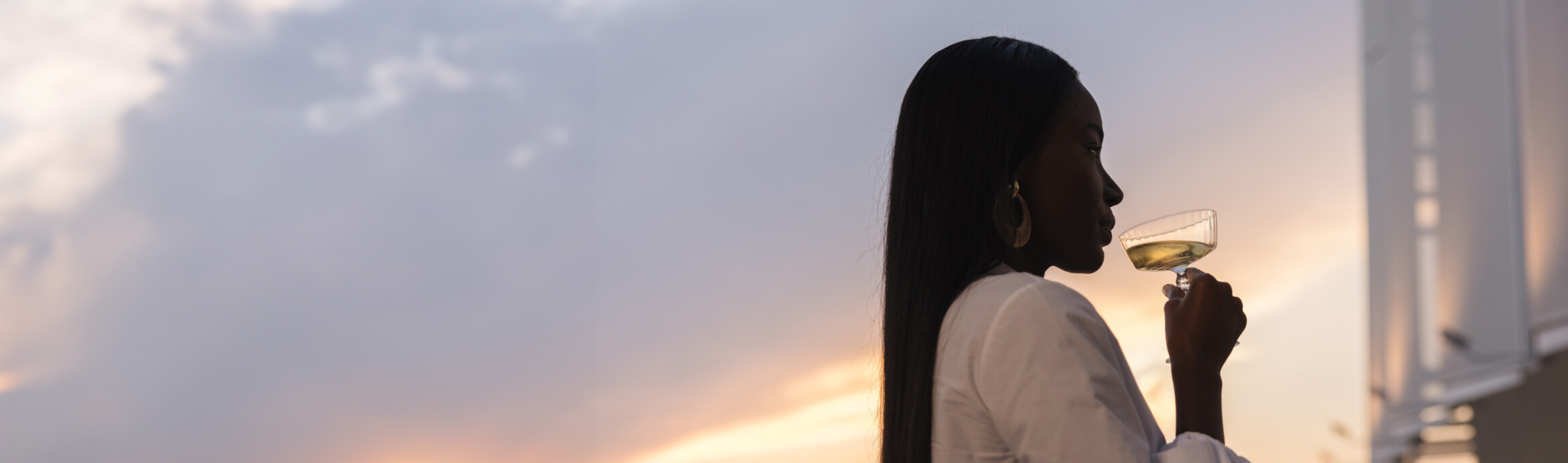 Woman sipping champagne at sunset, evoking the luxury lifestyle of The Residences at The St. Regis Nashville