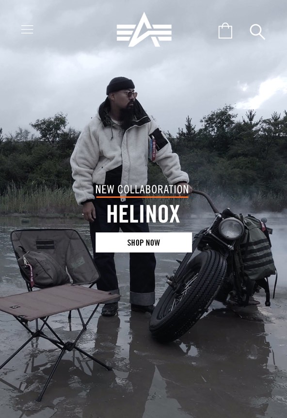Alpha Industries x Helinox collaboration mobile campaign showing a model in a sherpa jacket beside a motorcycle and Helinox camp chair