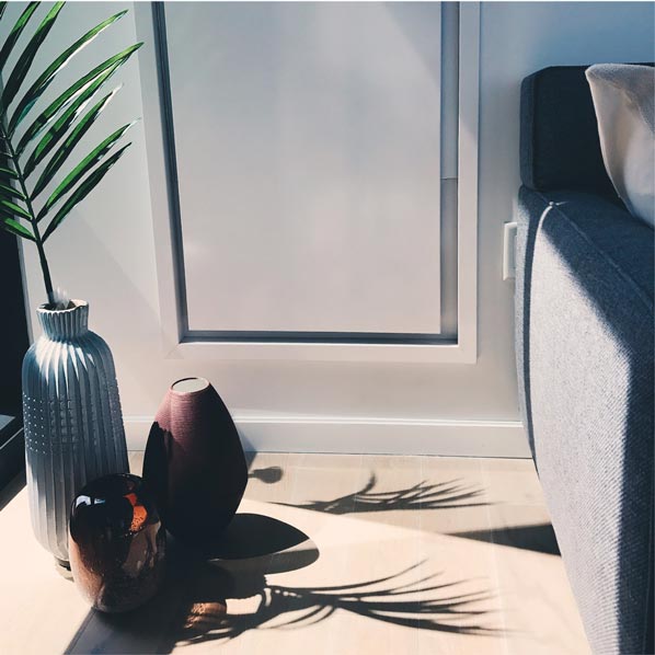 Styled apartment corner with ceramic vases and a palm plant casting dramatic shadows in an American Copper Building residence, social content by The Charles Group