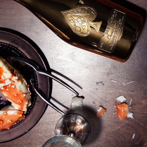 Armand de Brignac champagne bottle alongside a crab dining scene, produced for luxury Instagram grid content by The Charles Group