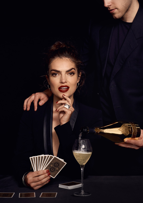 Armand de Brignac champagne social content produced by The Charles Group, featuring editorial lifestyle photography of a woman playing cards while champagne is poured