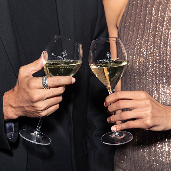 Two Armand de Brignac branded champagne flutes raised in a toast, from luxury social media content produced by The Charles Group