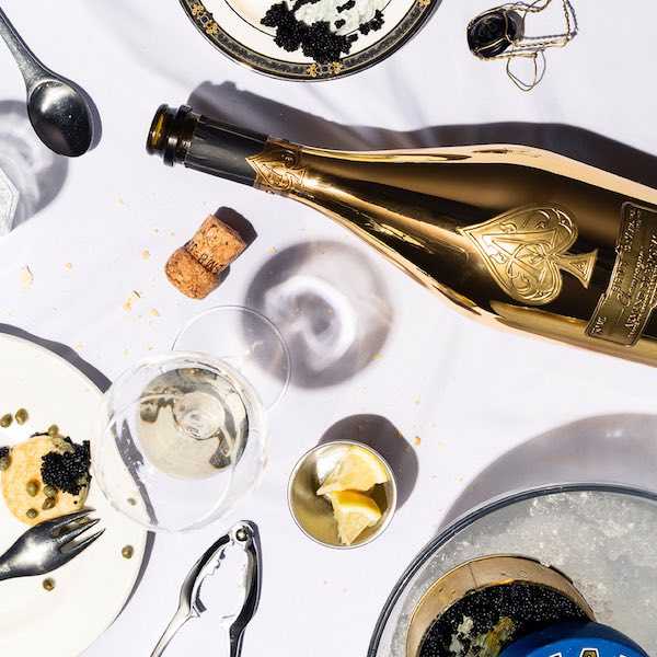 Armand de Brignac gold champagne bottle flat lay with caviar and luxury tableware, produced for Instagram grid content by The Charles Group