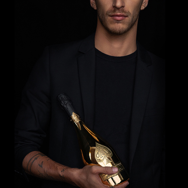 Male lifestyle portrait holding an Armand de Brignac gold Ace of Spades bottle, produced for luxury social media content by The Charles Group