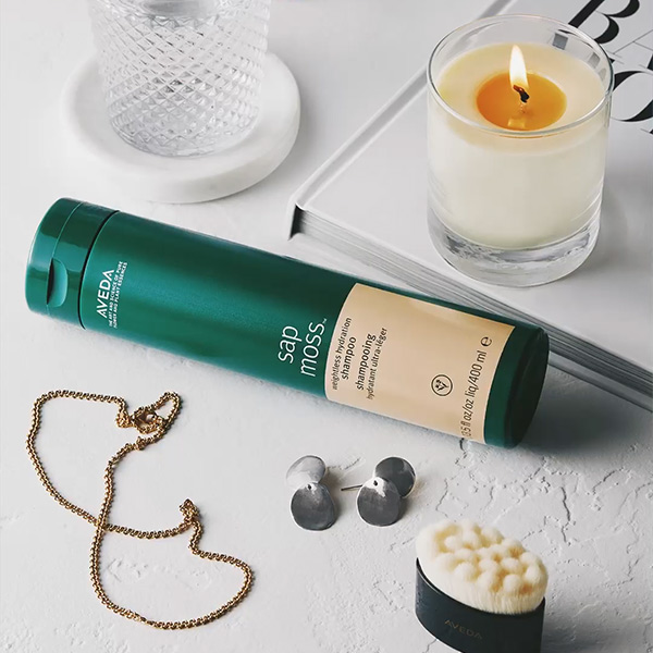 Five-star customer review graphic for Aveda Sap Moss shampoo over a product texture background, social content by The Charles Group