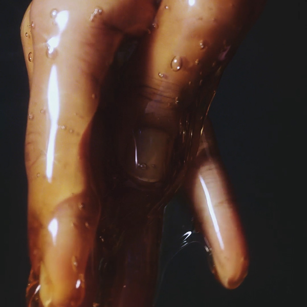 Hands coated in a golden amber liquid ingredient for Aveda Sap Moss haircare, macro video still produced by The Charles Group