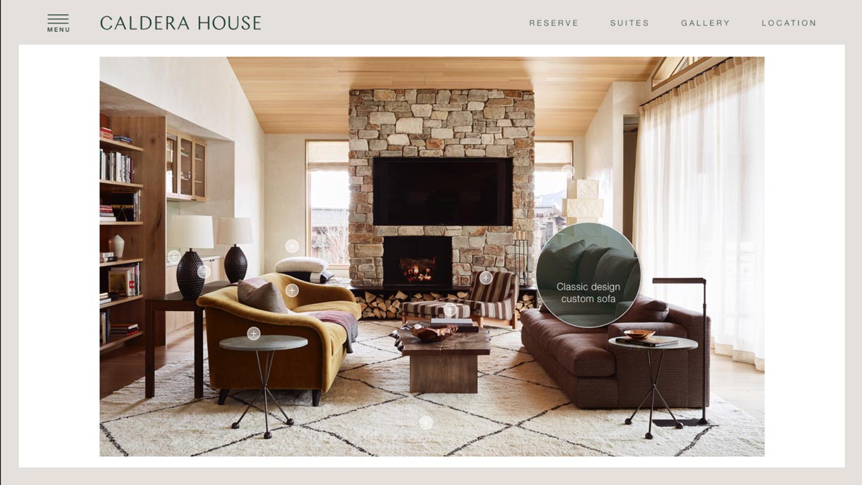 Caldera House suite page with interactive hotspot highlighting a classic design custom sofa by stone fireplace