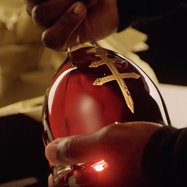 Hands cradling a D'ussé cognac bottle, highlighting the signature gold cross emblem, from the D'ussé Holiday social campaign by The Charles Group