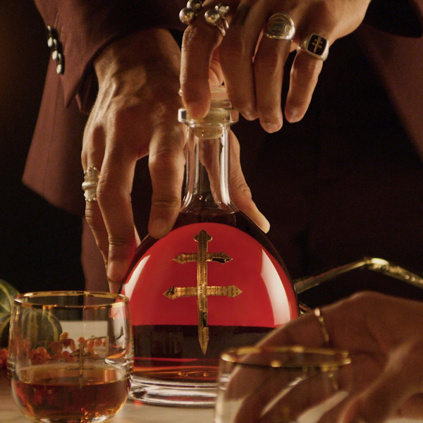 Bejeweled hands reaching for a D'ussé cognac decanter at a holiday dinner table, social content created by The Charles Group