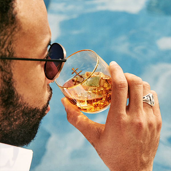 Man in sunglasses sipping D'ussé cognac on the rocks beside a pool, D'ussé social content by The Charles Group