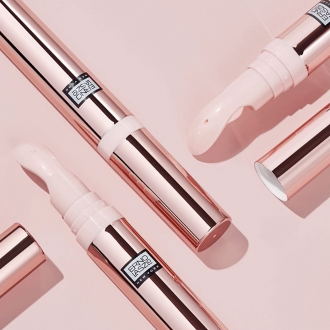 Flat lay of multiple Erno Laszlo Multi-Task Eye Gel Cream rose gold applicator pens on pink background