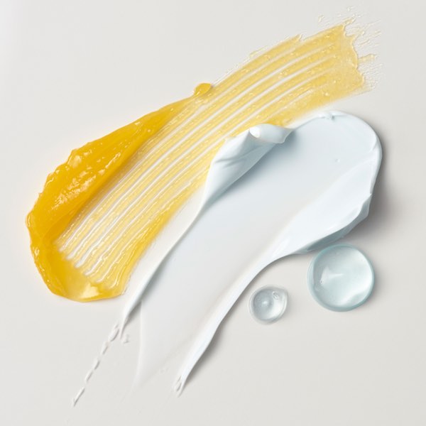 Close-up of Erno Laszlo skincare formula texture swatches in yellow and white