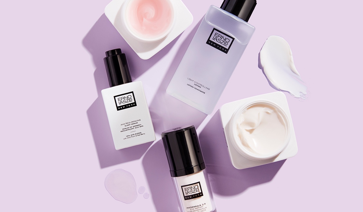 Erno Laszlo skincare product flatlay including AHA Sleep Serum, toner, and eye cream on a lavender background
