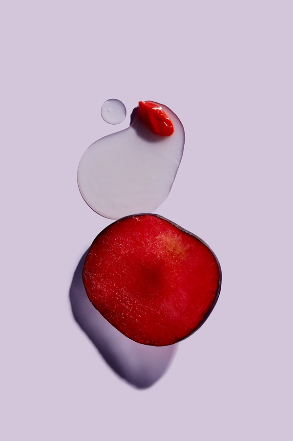 Sliced wild plum fruit next to AHA serum droplet, highlighting key Erno Laszlo resurfacing serum ingredients