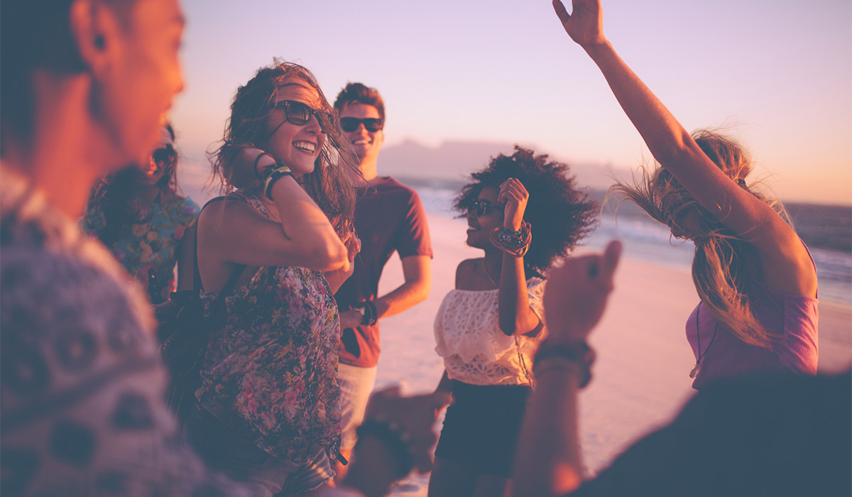 Group of friends dancing and celebrating on a beach at sunset, featured in Hard Rock Hotels paid media campaign by The Charles Group