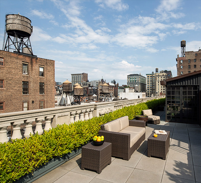 Private rooftop terrace with outdoor seating overlooking the New York City skyline and water towers