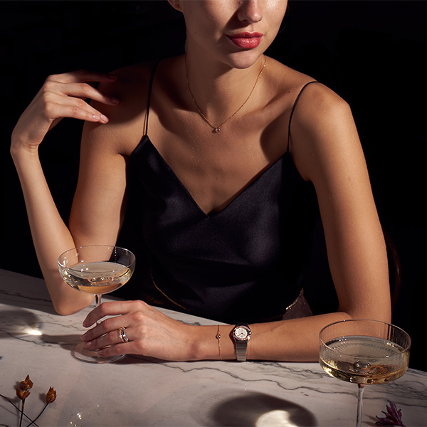 Woman in winter coat wearing Omega watch while holiday shopping on a city street, by The Charles Group