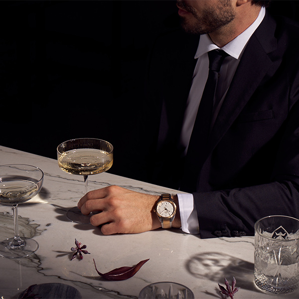 Two people toasting with wine glasses at an intimate holiday dinner, Omega watch campaign by The Charles Group