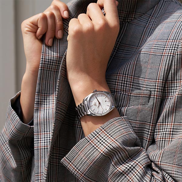 Close-up of an Omega watch on a woman's wrist against a dark background