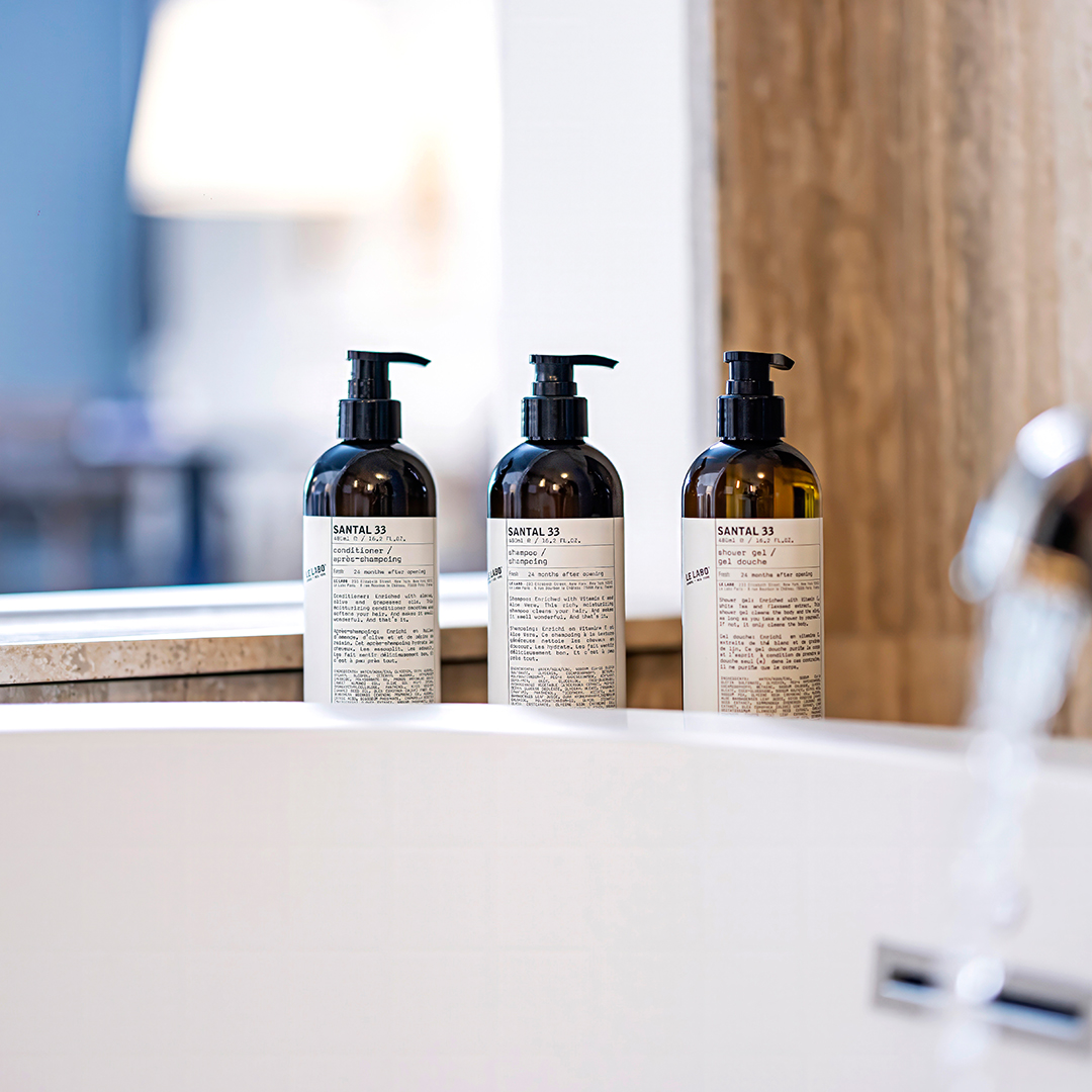 Three Le Labo Santal 33 amenity bottles — conditioner, shampoo, and shower gel — displayed on a bathroom counter at The Seagate Delray, from The Charles Group hospitality content campaign