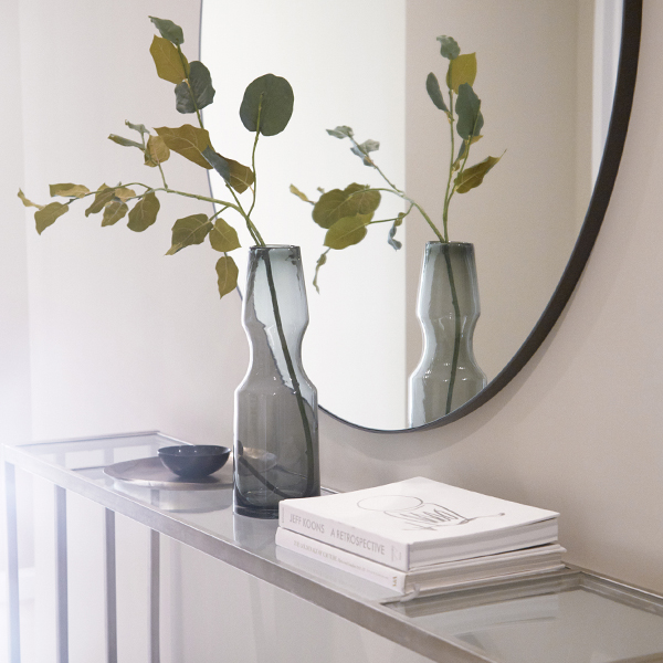 Minimalist entryway console with sculptural smoked glass vases and a round mirror in a Waterline Square luxury rental