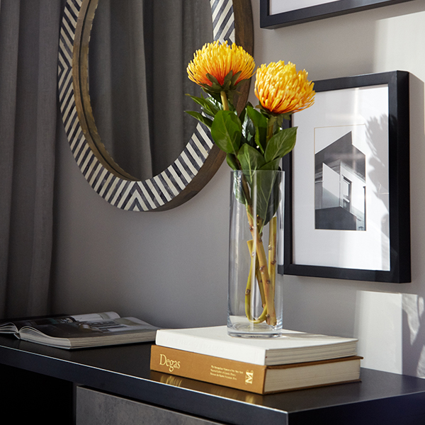 Styled console table with yellow chrysanthemums, art books, and a round mirror in a Waterline Square luxury apartment interior