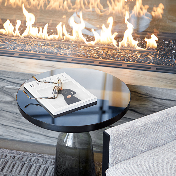 Side table with a Cereal magazine and reading glasses beside a lit outdoor fireplace at Waterline Square luxury residences NYC