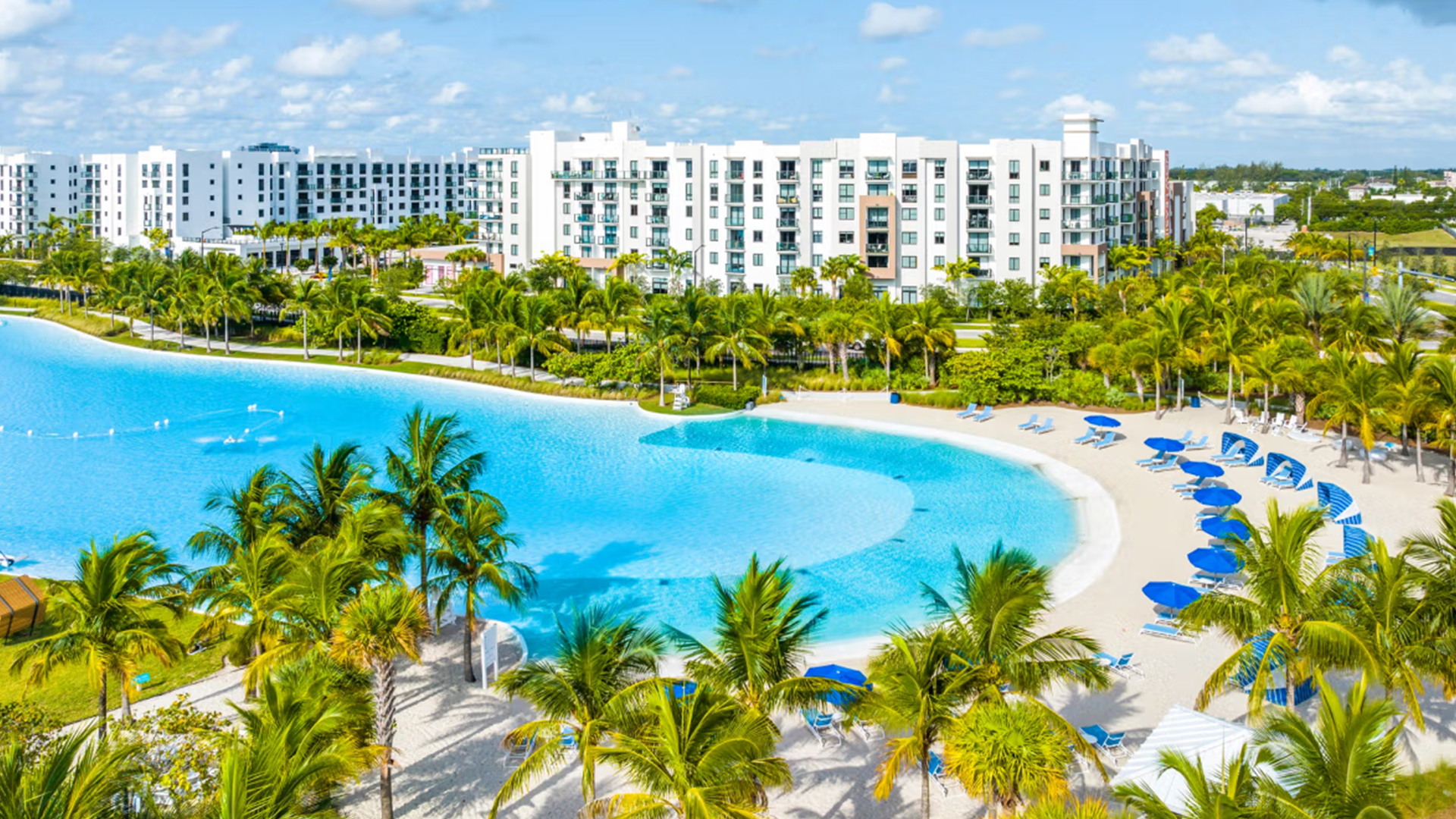 Aerial view of Turnberry's crystal-blue lagoon pool surrounded by palm trees and luxury residential towers in South Florida
