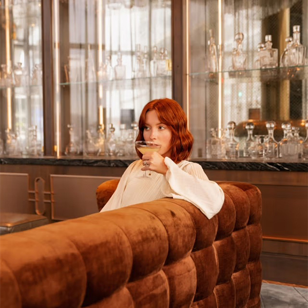 Woman enjoying a cocktail at an elegant Turnberry luxury hotel bar with crystal decanters, part of The Charles Group content campaign