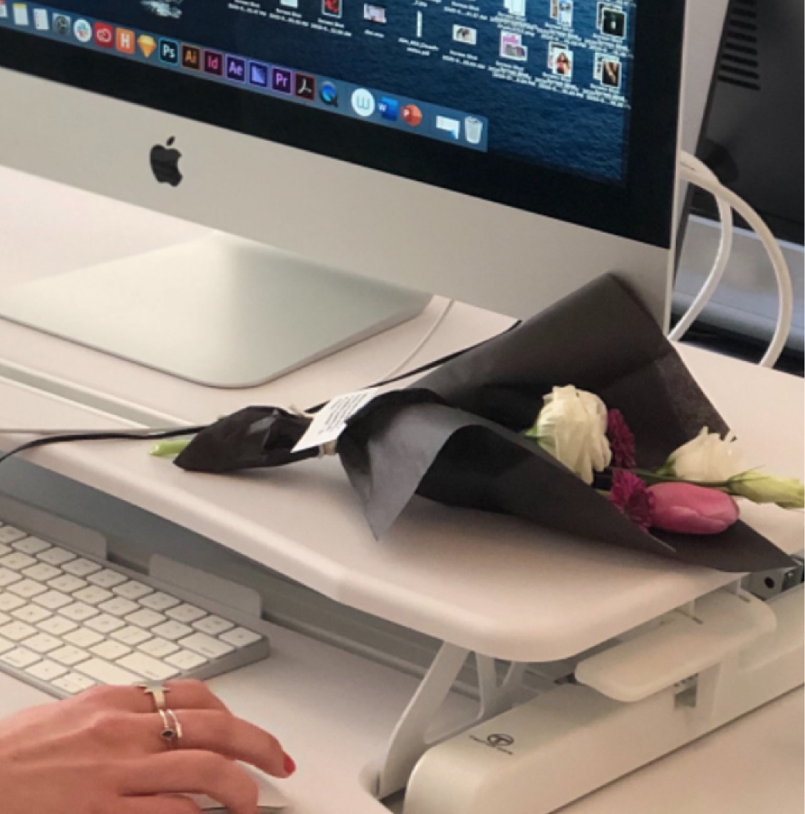 Wrapped flower bouquet resting on a creative agency employee's desk next to an iMac