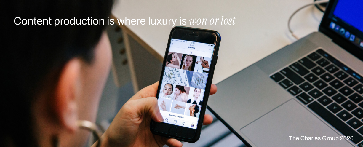 Over-the-shoulder shot of a person scrolling a luxury jewelry Instagram feed on a smartphone, representing how content production defines prestige brand perception